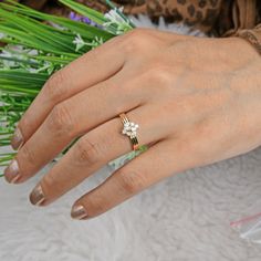 a close up of a person's hand with a flower ring on their finger