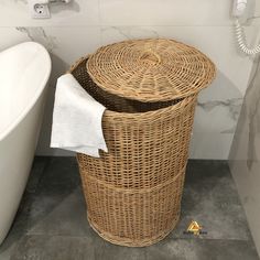 a wicker trash can next to a white bath tub