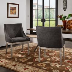 two gray chairs sitting on top of a rug in front of a table and windows