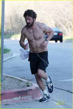 a shirtless man running down the street with headphones in his ears and earbuds