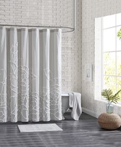 a white shower curtain in a bathroom next to a toilet and plant on the floor