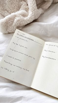 an open notebook sitting on top of a bed next to a stuffed animal and blanket