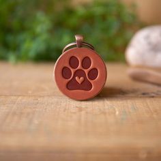 a dog's paw print on a red rubber keychain sitting on a wooden table