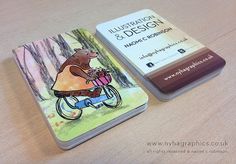 a book sitting on top of a wooden table next to a small card holder with an image of a bear riding a bike