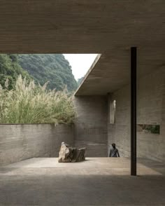 a person sitting on the ground in front of a building with large rocks and grass