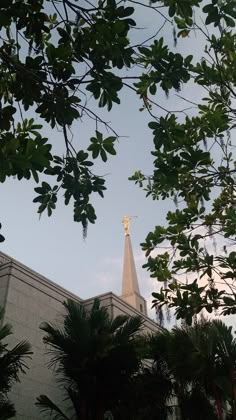 the top of a church with a cross on it's steeple surrounded by trees