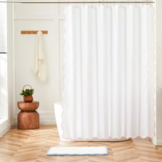 a white shower curtain with pink trim in a bathroom next to a potted plant