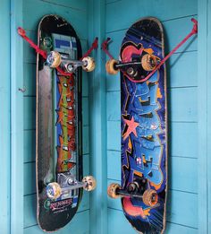 two skateboards mounted to the side of a blue wall next to each other,