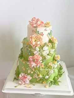 a three tiered cake decorated with flowers and leaves