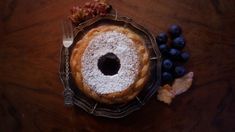 a pastry with powdered sugar and blueberries on a plate next to a fork