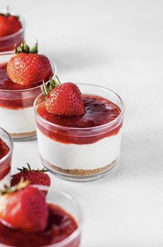 three small desserts with strawberries on top