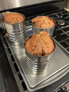 three tins filled with muffins sitting on top of an oven burner