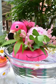 a pink flamingo planter sitting on top of a glass bowl filled with flowers