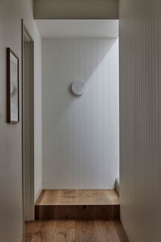 an empty hallway with wooden floors and white walls