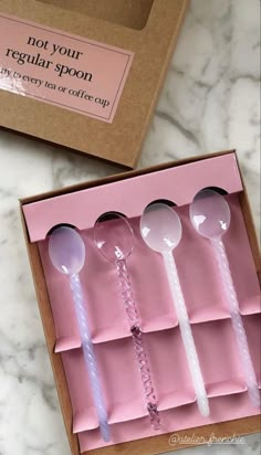 four spoons in a pink box on a marble table