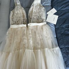 two dresses are laying on the bed with tags attached to them and one is white