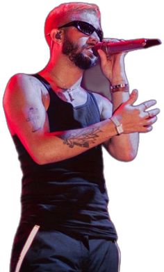 a man with tattoos on his arm holding a microphone and singing into the microphone while standing in front of a white background