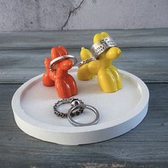 two yellow and orange teddy bears on a white tray with rings in front of them