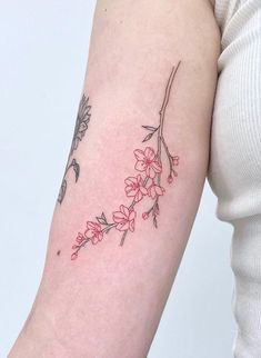 a woman's arm with red flowers and leaves on the left side of her arm