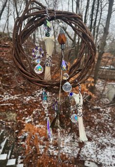 a wind chime hanging from the side of a tree in front of snow covered ground