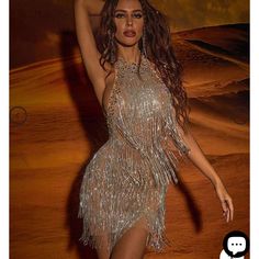 a woman in a silver fringe dress posing for a photo with her arms behind her head