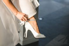 a close up of a woman's shoes with her hand on the shoe strap