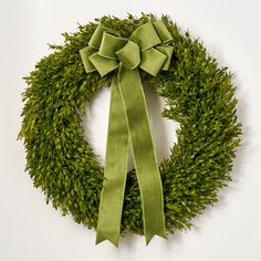 a green wreath with a bow hanging on the wall