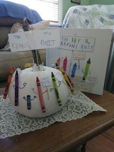 a white pumpkin sitting on top of a table next to some crayon markers