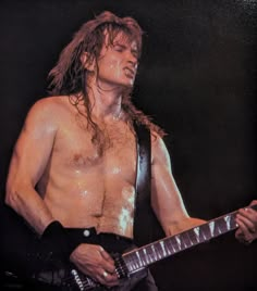 a shirtless man with long hair playing an electric guitar