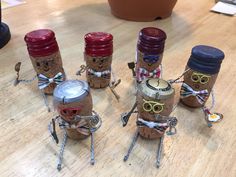 four corks with faces and glasses on them sitting on a table