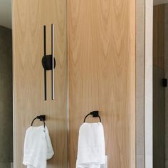 two white towels hanging on the wall next to a wooden door and mirror in a bathroom