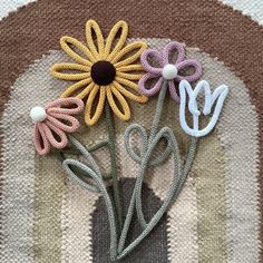 three crocheted flowers sitting on top of a rug