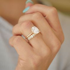 a woman's hand holding a ring with three stones on it and the middle finger