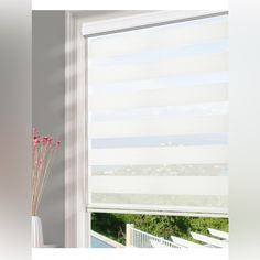 a vase with flowers in front of a window that has blinds on the windowsill