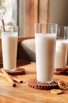 two glasses of milk sitting on top of a wooden table