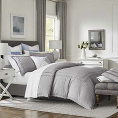 a bedroom with white walls and gray bedding