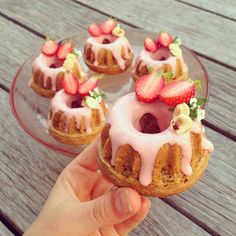 a hand holding a pastry with strawberries on top