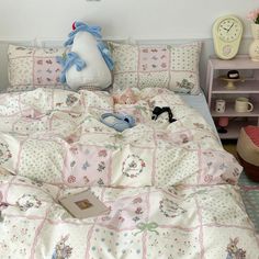 a bed covered in pink and white quilts with stuffed animals on top of it