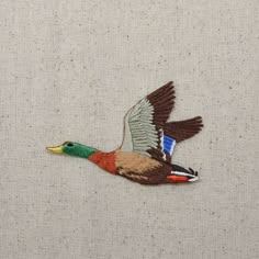 an embroidered bird is flying in the air