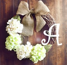 a wreath that has flowers on it with the letter f in front of it and a bow