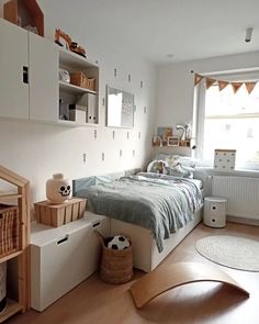 a bedroom with white walls and wooden flooring is pictured in this image, there are shelves on either side of the bed