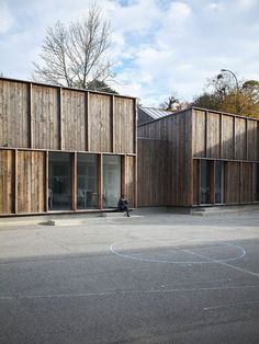 a person sitting on a bench in the middle of a parking lot next to wooden buildings