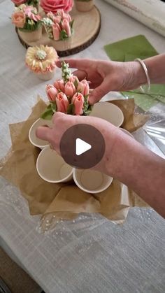 two hands are placing flowers in small bowls on a table with other plates and napkins