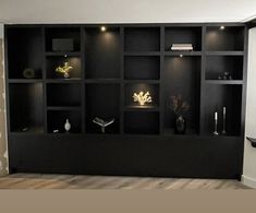 an empty room with black shelves and vases on the wall in front of it