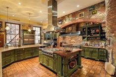 a large kitchen with green cabinets and an island in the middle of the room that is surrounded by brick walls