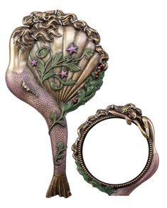 a mermaid tail shaped mirror next to a ring holder with flowers and leaves on it