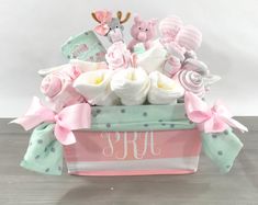 a pink and green basket filled with baby items on top of a wooden table next to a white wall