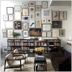 a living room filled with furniture and lots of framed pictures on the wall above it