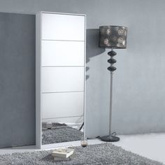 a mirror sitting on top of a white floor next to a lamp and a rug