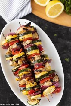 grilled vegetable kabobs on a white plate with lemons and parsley